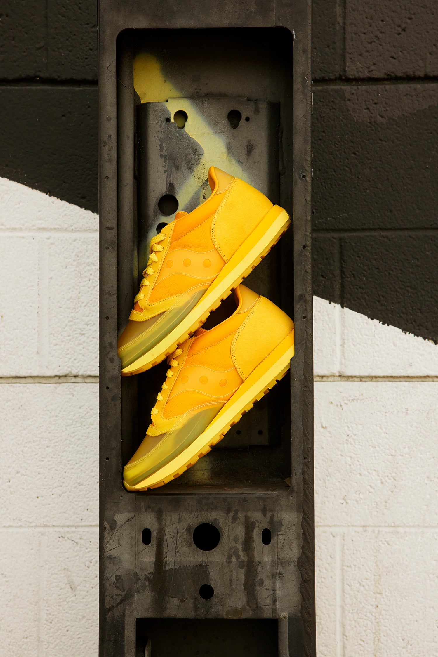 A pair of yellow sneaker on top of each other inside a grey stone box